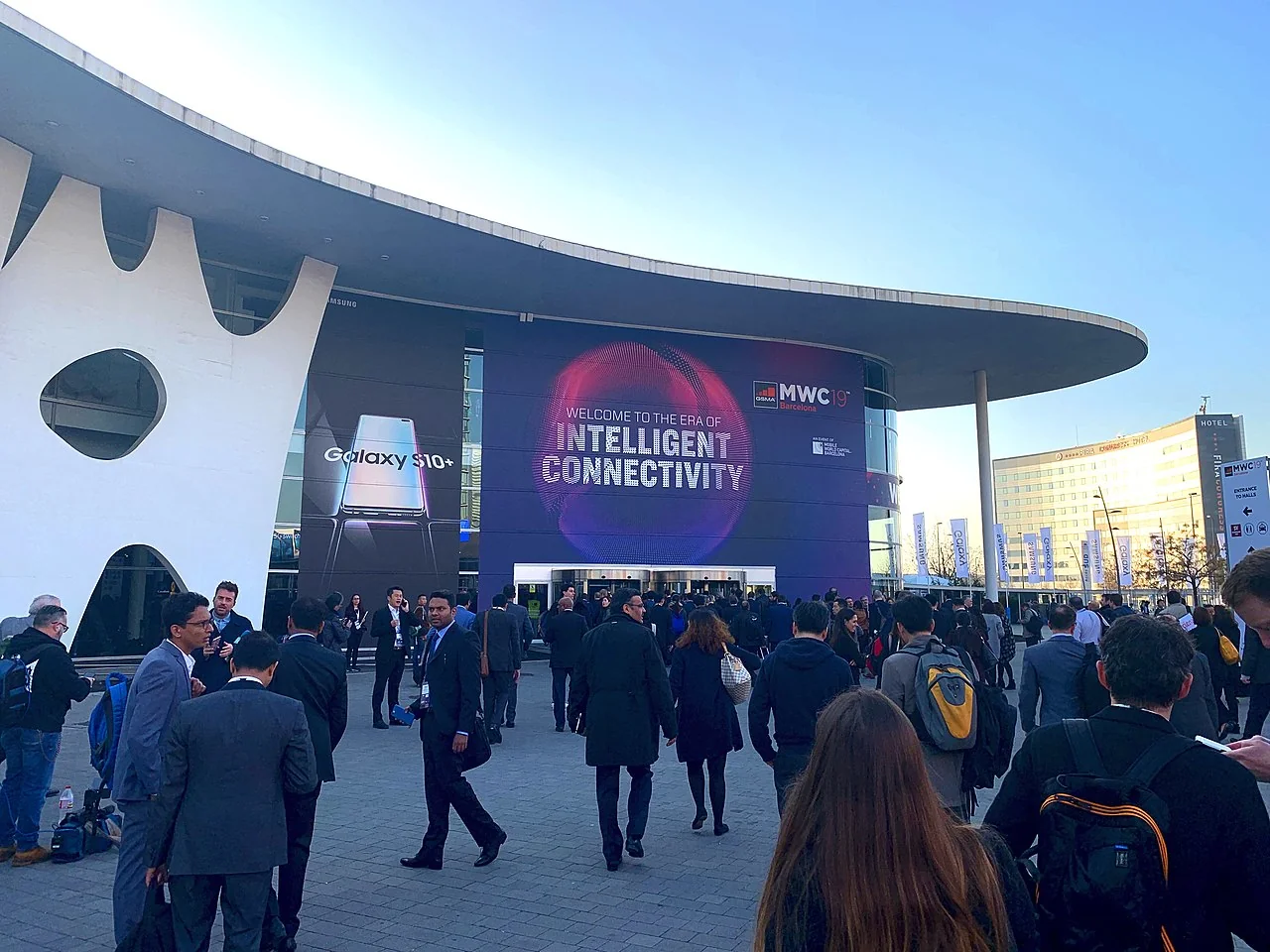 Tradeshow attendees in front of a modern building with a smartphone banner